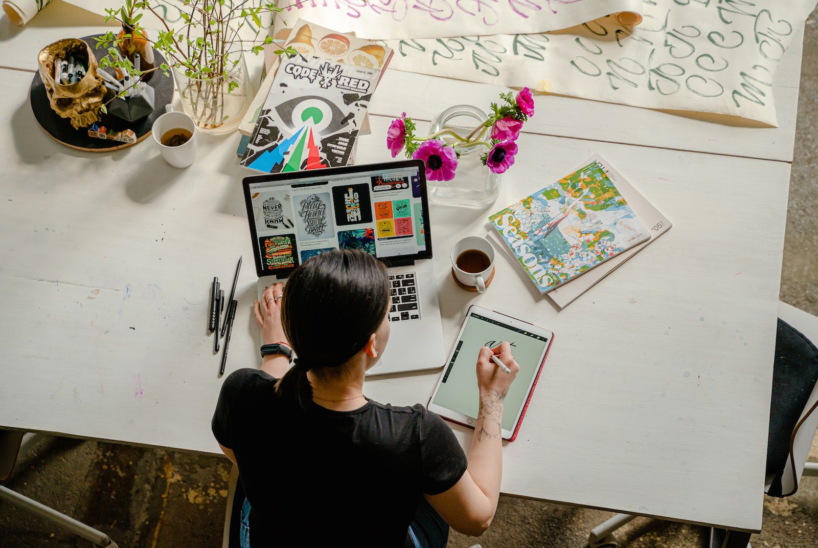 Foto de una mujer escribiendo en una tableta mientras usa una computadora portátil